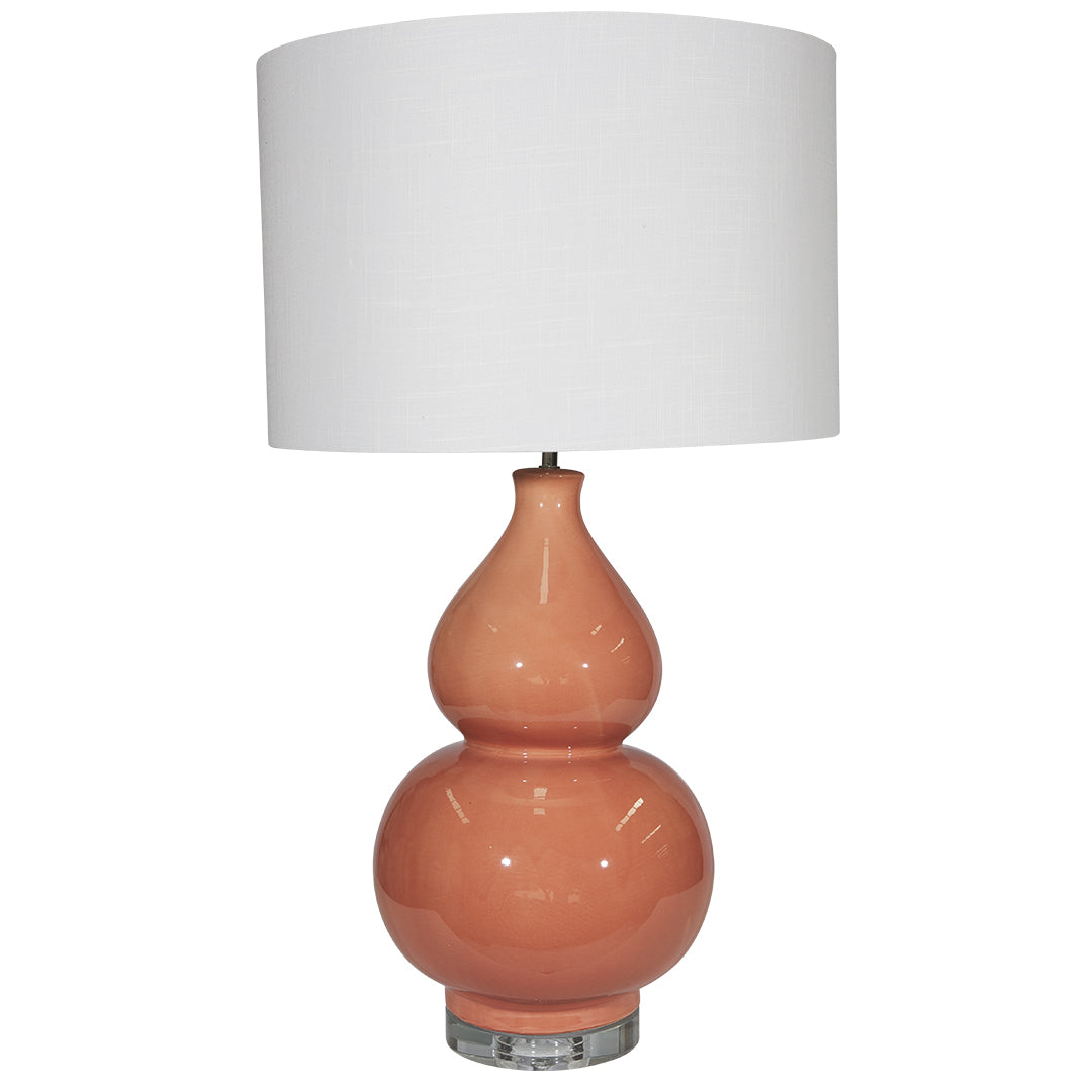 Table lamp with a peach-colored base and white shade on a white background