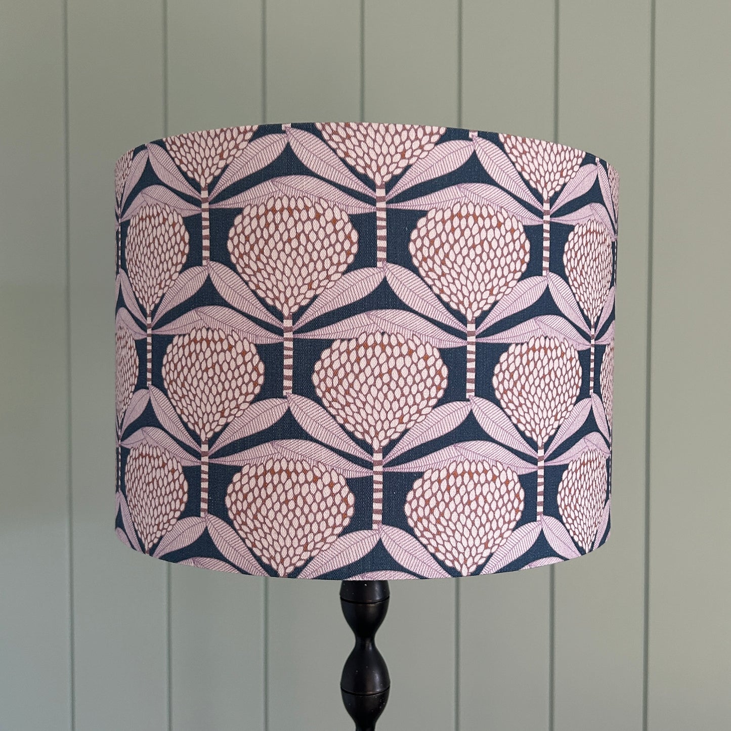 Decorative lampshade with a floral geometric pattern on a lamp stand against a wooden panel background