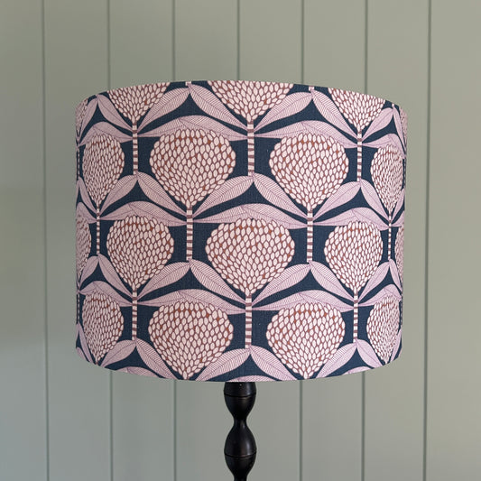 Decorative lampshade with a floral geometric pattern on a lamp stand against a wooden panel background