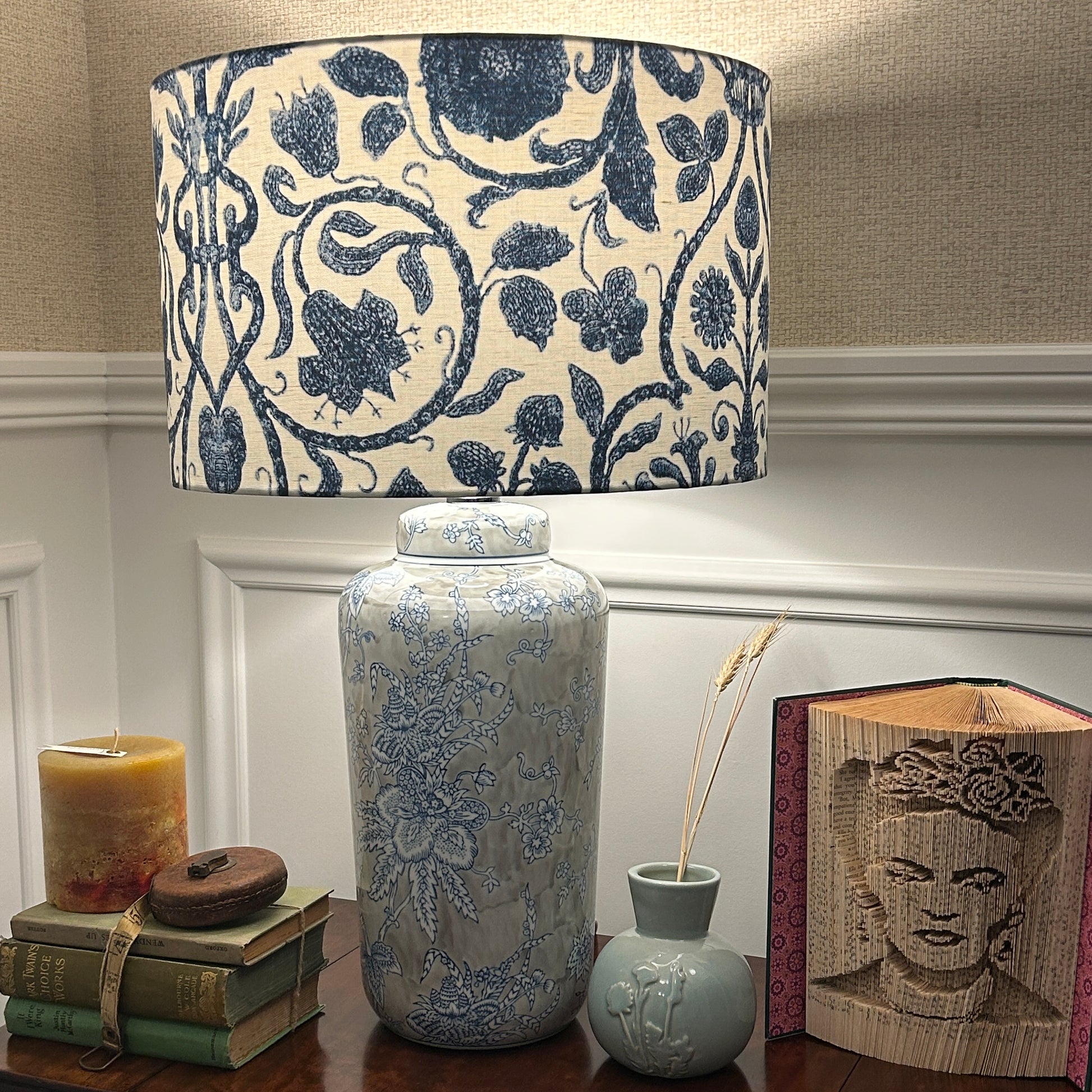 Decorative lamp with floral pattern on a wooden surface with books and a candle.