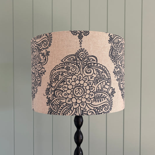 Decorative lampshade with paisley pattern against a wooden panel background