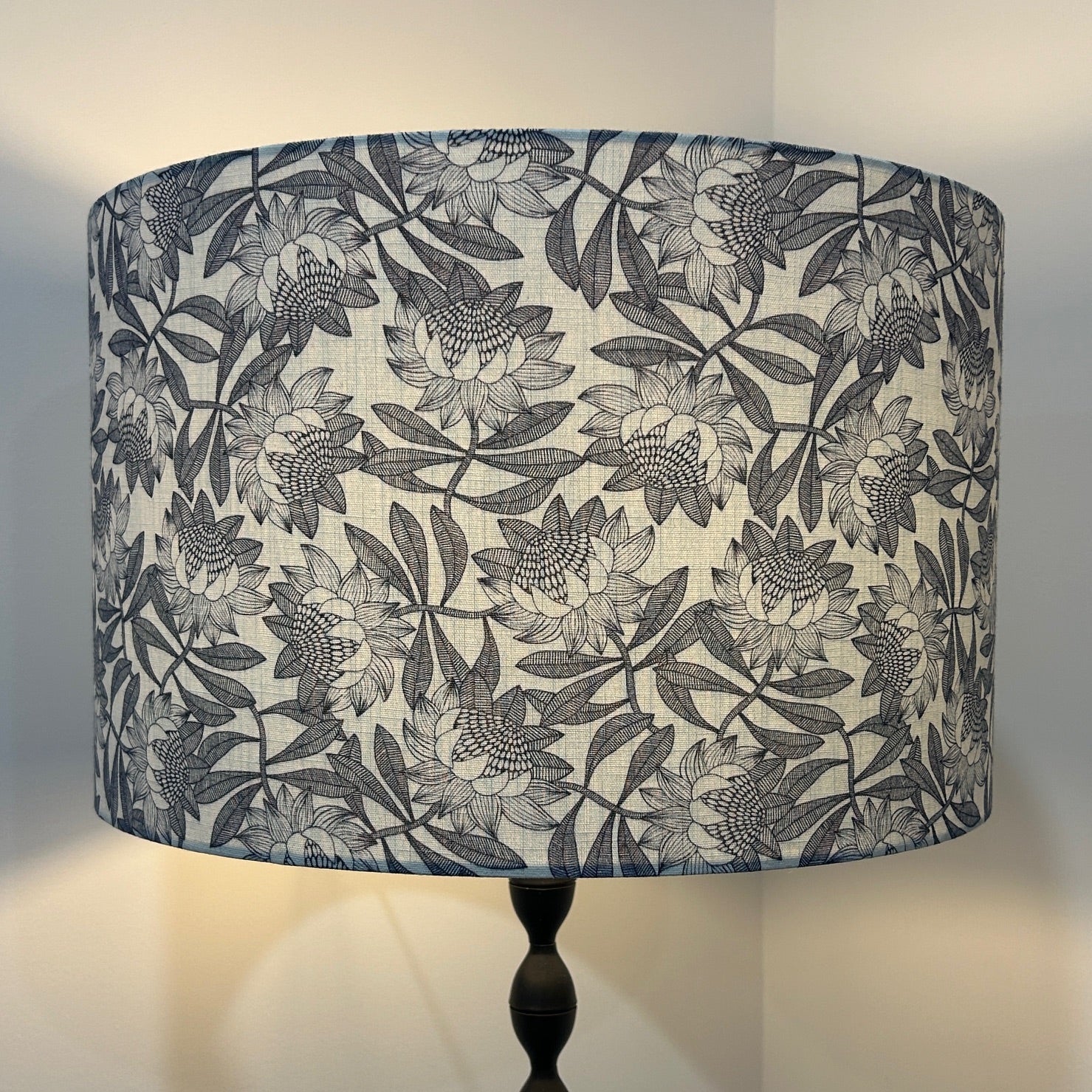 Navy and white protea pattern lampshade, lit up by lamp