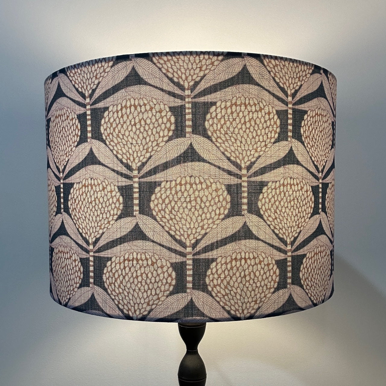 Banksia pattern deep blue handmade lampshade, lit up by lamp